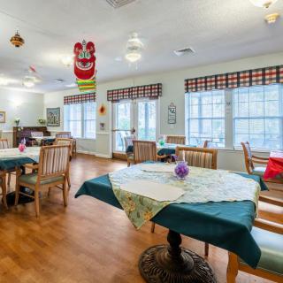 A cozy dining room with decorated tables and ample natural light streaming through large windows.