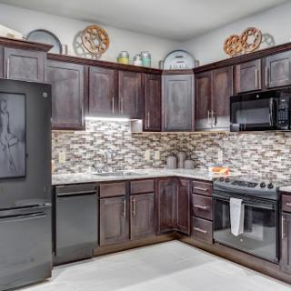 A modern kitchen featuring dark cabinetry, black appliances, and a stylish tile backsplash.
