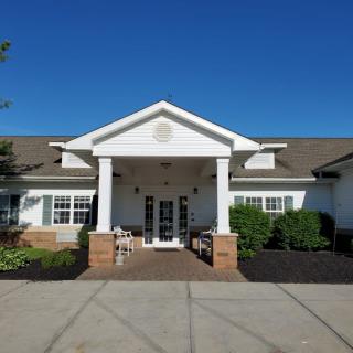 Front view of a white building with columns and a porch under a clear blue sky.