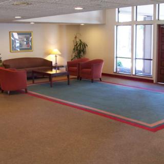 A hotel lobby with comfortable seating, including a sofa and chairs around a coffee table on a carpet.