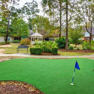 A tranquil outdoor garden with a gazebo, surrounded by trees and a manicured lawn.