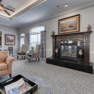 A well-decorated living room featuring a prominent fireplace, comfortable seating, and elegant artwork.