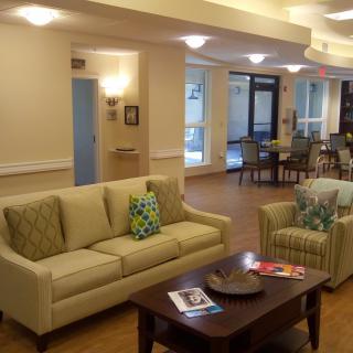 A cozy living room with a comfortable sofa and coffee table, featuring decorative cushions and soft lighting.