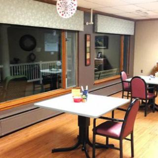 An interior view of a dining area with tables and chairs near large windows.