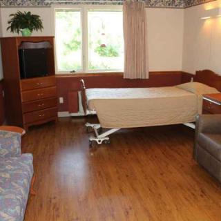 A hospital room with a bed, television, and wooden flooring.