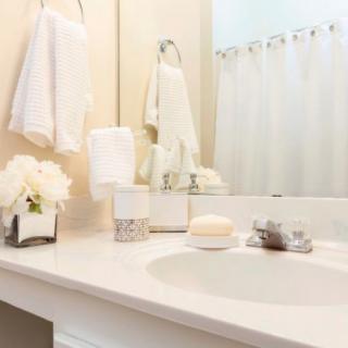 A clean and neatly organized bathroom countertop with towels, flowers, and soap.