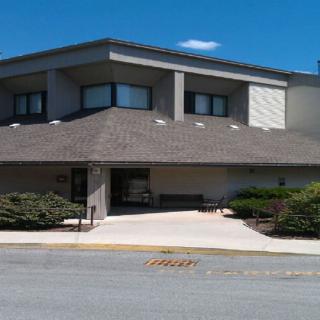 A suburban residential building with a landscaped entrance under a clear blue sky.
