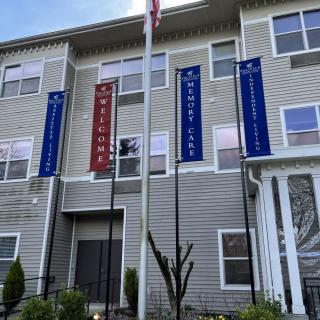 An apartment building with welcome signage and multiple flags displayed outdoors.