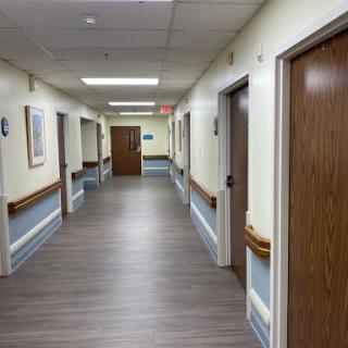 A corridor in a hospital with wooden doors and artwork on the walls.