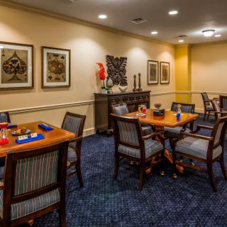 A cozy dining area with neatly arranged tables and chairs, decorated with wall art and ambient lighting.