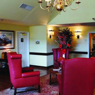 A cozy lobby area featuring red chairs, a chandelier, and decorative elements.