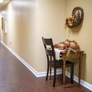 A hallway with autumn-themed decorations on a wooden table, including pumpkins and a festive wreath.