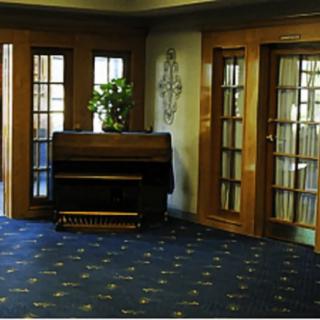 A cozy room featuring a piano, wooden doors, and an indoor plant on a carpeted floor.