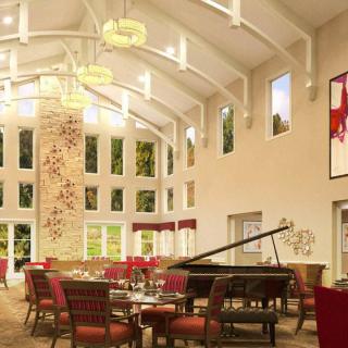 A spacious and elegantly designed interior featuring a grand piano, high ceilings, and decorative chandeliers.