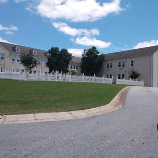 A view of a residential building with a well-maintained lawn under a partly cloudy sky.