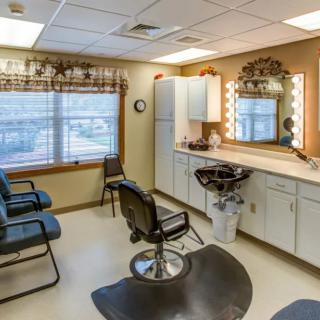 A cozy hair salon with multiple chairs, a large mirror, and overhead lighting.