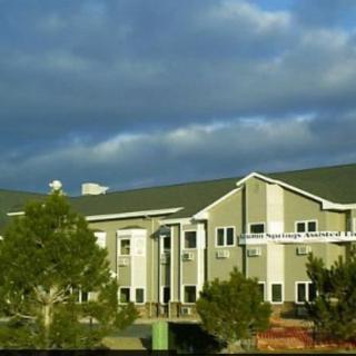A large building with a cloudy sky and trees in the foreground.