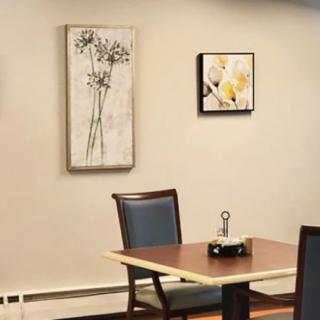 A cozy dining area with paintings on the wall and a neatly set table.
