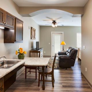 A modern open-concept kitchen and living room with wood flooring, featuring a dining table, sofa, and stylish decor.