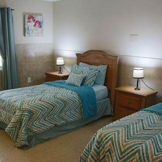 A cozy bedroom with two neatly made twin beds, matching bedding, and bedside lamps.