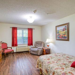 A cozy bedroom featuring a bed, chairs, and colorful decor.