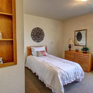 A cozy bedroom with a single bed, decorative items, and wooden furniture.