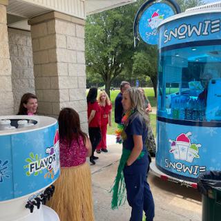 A lively outdoor event featuring a snow cone stand, where attendees enjoy flavored treats.