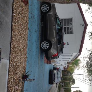 Cars parked in a suburban driveway in front of a house.