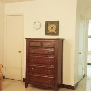 A wooden dresser stands against a wall, complemented by a wall clock and framed artwork.