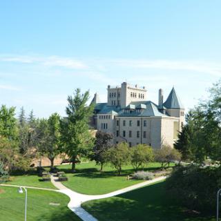 A picturesque view of a castle surrounded by lush greenery and clear blue skies.