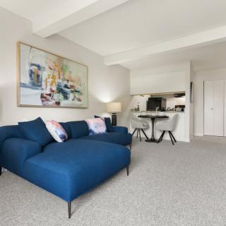A modern, minimalist living room with a blue sofa and contemporary artwork on the wall.