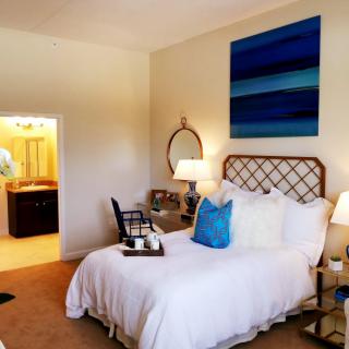 A cozy bedroom featuring a stylish bed, decorative pillows, and a modern painting on the wall.