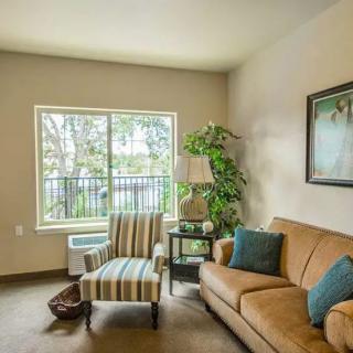 A cozy living room with a sofa, armchair, and a large window letting in natural light.