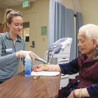 A healthcare worker assists an elderly patient in a hospital setting.