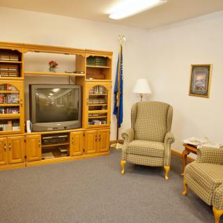 A cozy living room with an entertainment center and armchairs.