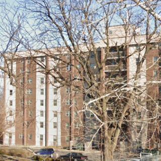 A residential apartment building surrounded by bare trees on a clear day.