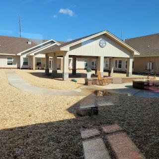 A view of a modern residential building with an open courtyard, surrounded by gravel and a clear blue sky.