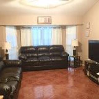 A cozy living room with black leather sofas and a television.