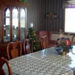 A cozy dining room with a decorated table and a china cabinet, featuring holiday decorations.
