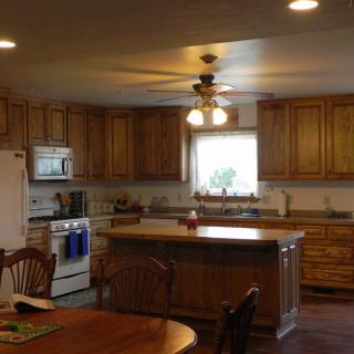 A spacious kitchen with wooden cabinets, a central island, and a dining area.