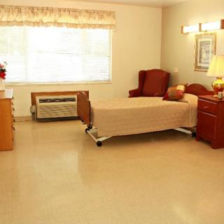 A clean and tidy hospital room with a bed and furniture.