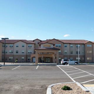 A hotel with a parking lot in front under a clear blue sky.