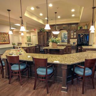 A modern kitchen with a large countertop and bar seating, illuminated by pendant lights.