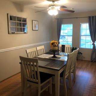 A cozy dining room with a wooden table and chairs, featuring decor elements like sunflowers and wall art.