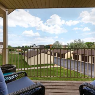 A cozy balcony overlooking a neighborhood with comfortable seating and a cloudy sky above.