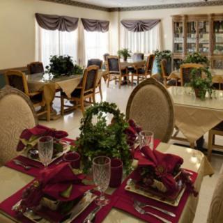 An elegantly set dining room with neatly arranged tables and decorative plants.