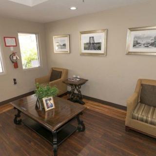 A cozy living room with a coffee table, chairs, and framed artwork on the walls.