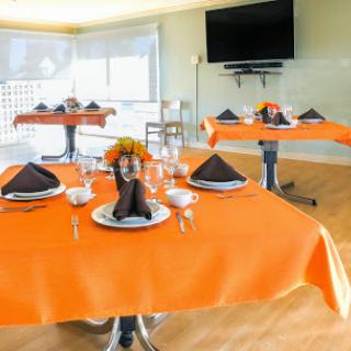 An elegantly set dining area with vibrant orange tablecloths and decorative elements, perfect for a special occasion.