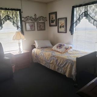 A cozy bedroom featuring a single bed, bedside lamp, and decorative curtains.