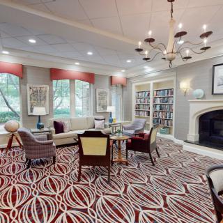 A cozy library interior with comfortable seating, bookshelves, and a fireplace.